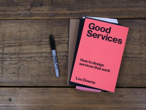 Boken «Good Services – How to design services that work» av Lou Downe ligger på et grovt trebord.